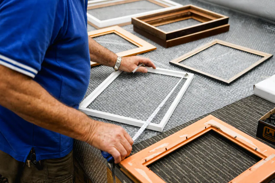A Frameshop framer measuring custom frames in the workshop